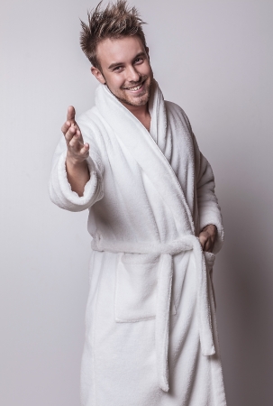 Beautiful adult man on white bathrobe brushing teeth   の写真素材