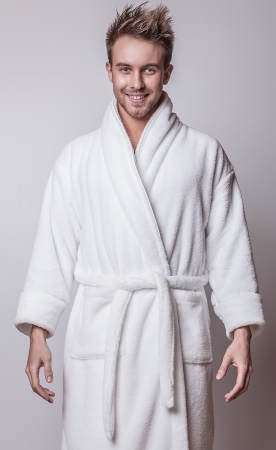 Beautiful adult man on white bathrobe brushing teeth   の写真素材