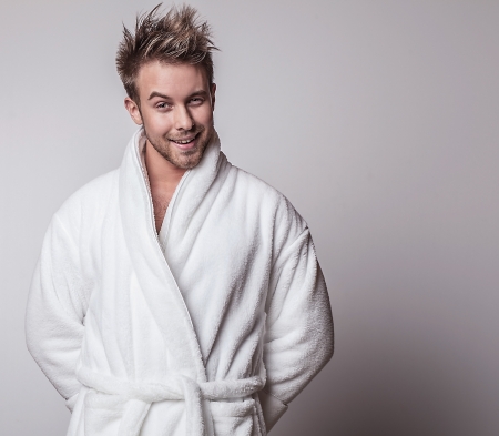 Beautiful adult man on white bathrobe brushing teeth   の写真素材
