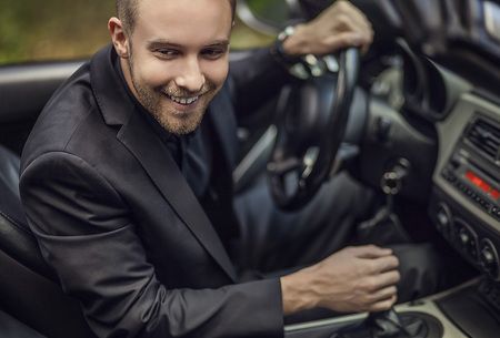 Elegant young happy man in convertible car outdoor   の写真素材