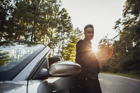 Elegant young happy man in convertible car outdoor   
