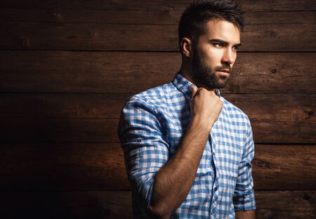 Portrait of young beautiful fashionable man against wooden wall の写真素材
