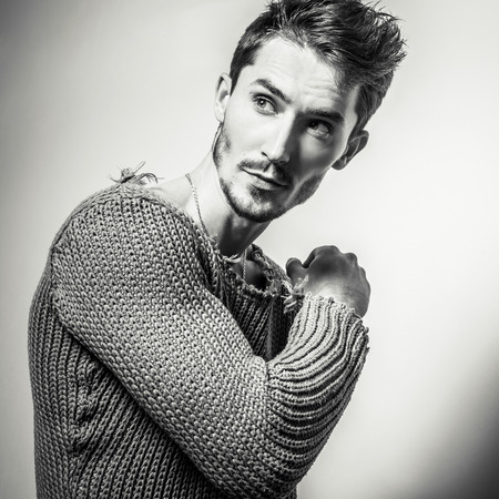 Black-white studio portrait of young handsome man in knitted sweater. Close-up photo.の写真素材