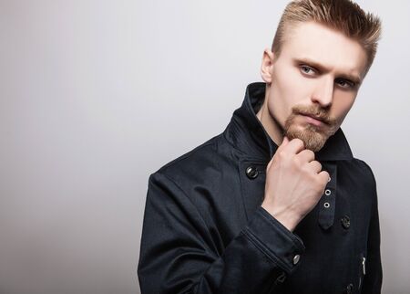 Elegant young handsome man in black coat. Studio fashion portrait.の写真素材