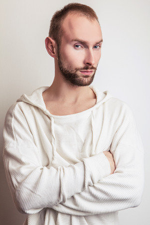 Studio portrait of young handsome man in white sweater with hood.の写真素材
