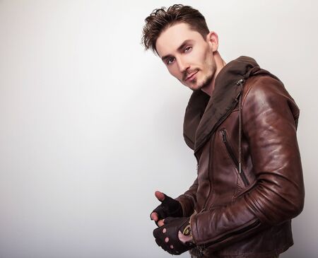 Attractive young man in a brown leather jacket pose in studio.の写真素材