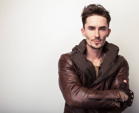Attractive young man in a brown leather jacket pose in studio.の写真素材