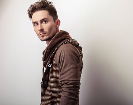 Attractive young man in a brown sweater pose in studio.の写真素材