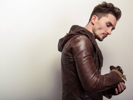 Attractive young man in a brown leather jacket pose in studio.の写真素材