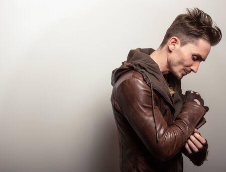 Attractive young man in a brown leather jacket pose in studio.の写真素材