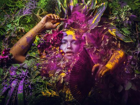 Fairy tale girl portrait surrounded with natural plants and flowers. Art image in bright fantasy...