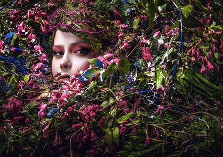 Fairy tale girl portrait surrounded with natural plants and flowers. Art image in bright fantasy...