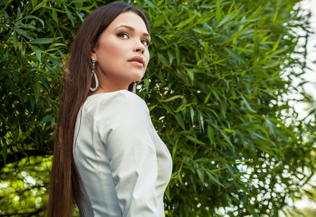 Outdoors portrait of beautiful young girl in luxury white dress posing in summer garden.の写真素材
