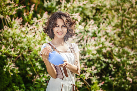 Outdoors portrait of beautiful  positive young woman in overalls which posing in solar summer garden.の写真素材