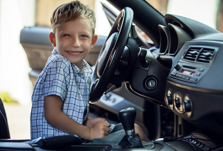 Outdoor portrait of happy blond little boy who explore salon of sport auto.の写真素材