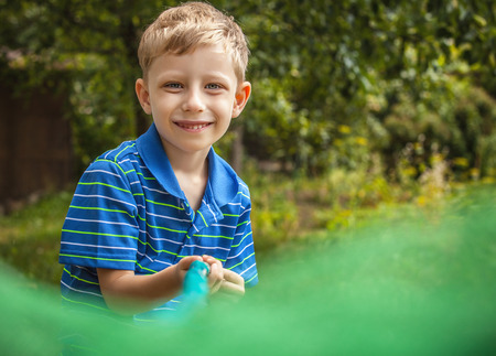 Outdoor portrait of happy little boy with net for butterflies posing in summer garden.の写真素材