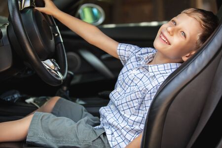 Outdoor portrait of happy blond little boy who explore salon of sport auto.の写真素材