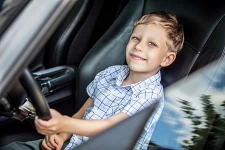 Outdoor portrait of happy blond little boy who explore salon of sport auto.の写真素材