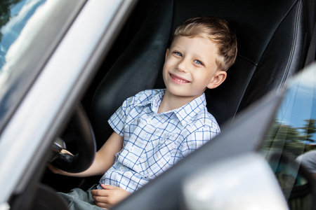 Outdoor portrait of happy blond little boy who explore salon of sport auto.の写真素材