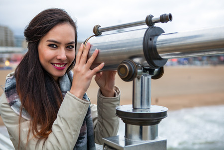 Beautiful young woman with magnificent hairs near telescope on pier in the Hague.の写真素材