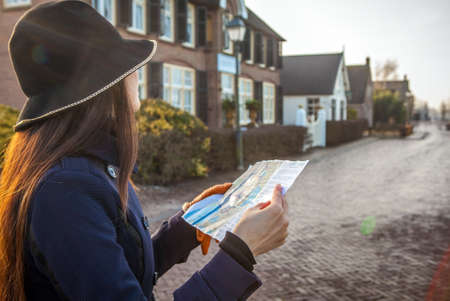 Outdoors portrait of attractive young woman with long beautiful hairs and city map in hands.の写真素材