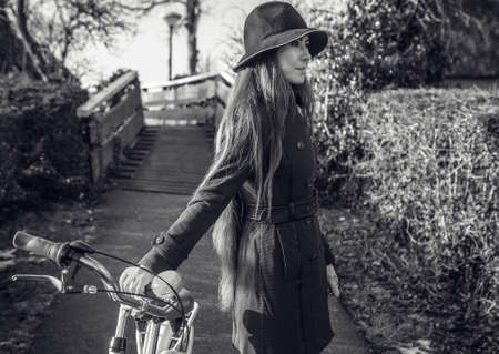 Outdoors portrait of attractive young woman with white bicycle