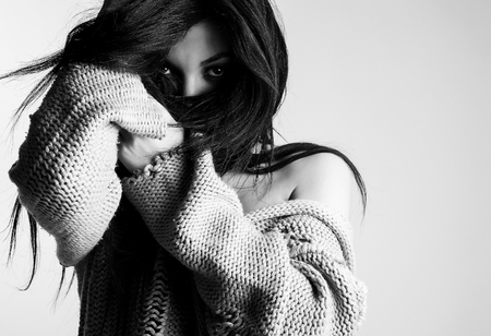 Beautiful young brunette in a woolen sweater pose against studio  background. Black-white fashion Photo.の写真素材