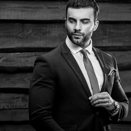 Portrait of young beautiful fashionable man against wooden wall.の写真素材