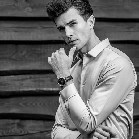 Portrait of young beautiful fashionable man against wooden wall.の写真素材