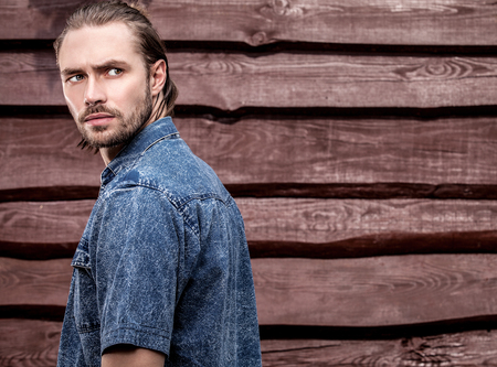 Portrait of young handsome man against wooden wall.の写真素材