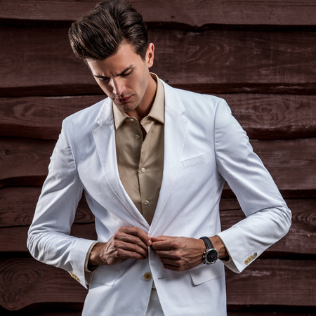 Portrait of young beautiful fashionable man against wooden wall.