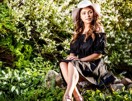 Outdoors portrait of beautiful young woman in white classic hat.の写真素材