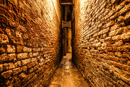 Ancient narrow streets and facades of old medieval buildings at night time close-up. Venice, Italy.の写真素材