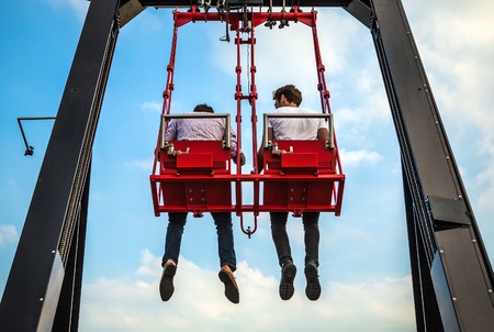 People having fun In swing carousel against blue sky.の写真素材