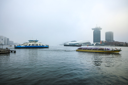 AMSTERDAM, NETHERLANDS - JANUARY 02, 2017: Boats on city channel near pier of Central station in foggy day. January 02, 2017 in Amsterdam - Netherland.のeditorial素材