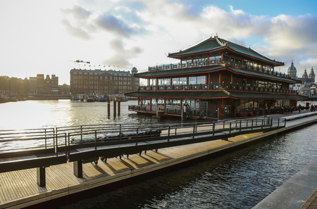 AMSTERDAM, NETHERLANDS - DECEMBER 28, 2016: Famous buildings and place of Amsterdam city centre at sun set time. General landscape view. December 28, 2016 - Amsterdam - Netherlands.のeditorial素材