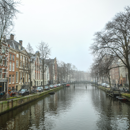 AMSTERDAM, NETHERLANDS - DECEMBER 28, 2016: Famous buildings and place of Amsterdam city centre at sun set time. General landscape view. December 28, 2016 - Amsterdam - Netherlands.のeditorial素材