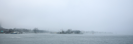 General view of city channel near pier of Amsterdam Central station in foggy day.の写真素材