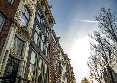 AMSTERDAM, NETHERLANDS - JANUARY 09, 2017: Famous vintage buildings of Amsterdam city at sun set. General landscape view at tradition Dutch architecture. January 09, 2017 - Amsterdam - Netherlands.のeditorial素材