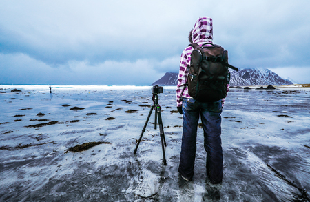 Travel photographer doing pictures outdoor at evening time. Lofoten islands. Beautiful Norway landscape.の写真素材
