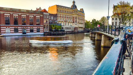 The most famous canals and embankments of Amsterdam city during sunset. General view of the cityscape and traditional Netherlands architecture.の写真素材