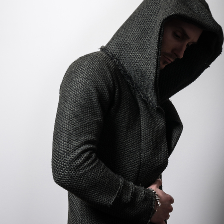 Handsome young sporty man in dark green hoodie pose against gray studio background.の写真素材