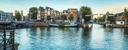 The most famous canals and embankments of Amsterdam city during sunset. General view of the cityscape and traditional Netherlands architecture.のeditorial素材