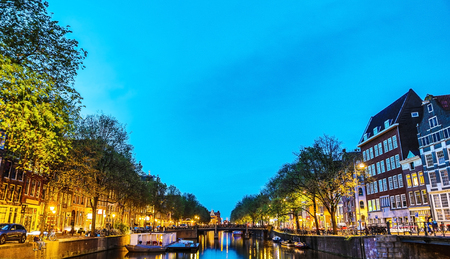 The most famous canals and embankments of Amsterdam city during sunset. General view of the cityscape and traditional Netherlands architecture.のeditorial素材