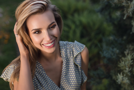 Outdoors portrait of beautiful young woman in casual clothes posing in autumn garden.の写真素材