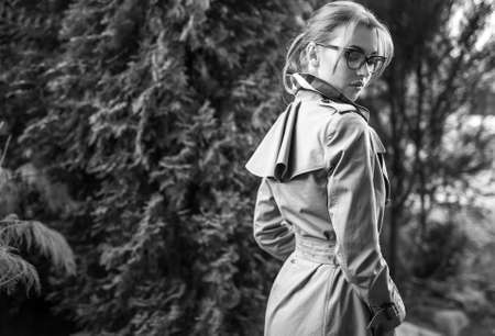 Outdoors black-white portrait of beautiful young woman in glasses against autumn garden.の写真素材