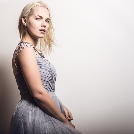 Young blond sensual model in a stylish dress pose in studio.の写真素材