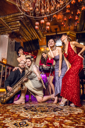 Group of young stylish people dressed classical style in interior of luxury club.の写真素材