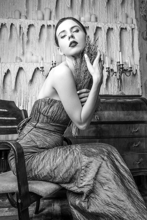 Beautiful young girl in stylish retro clothes posing in luxurious interior. Black-white portrait.の写真素材