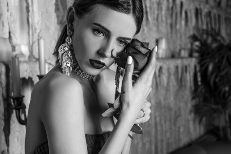 Beautiful young girl in stylish retro clothes posing in luxurious interior. Black-white portrait.の写真素材